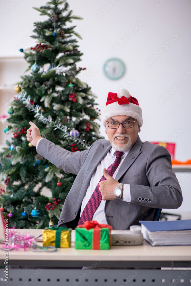 Aged male employee celebrating Christmas at workplace