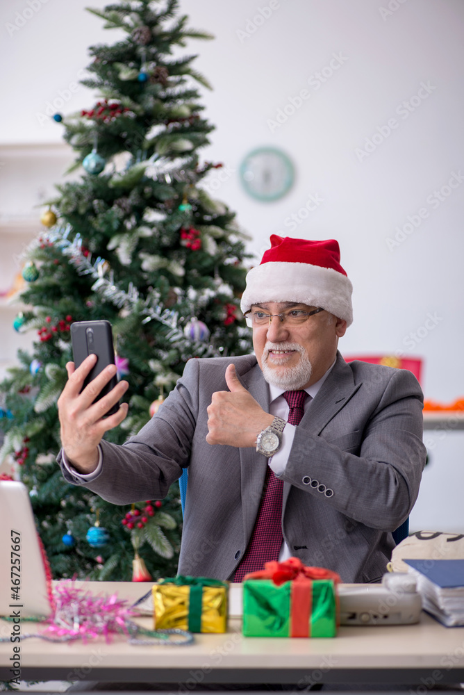 Aged male employee celebrating Christmas at workplace Aged male employee celebrating Christmas at workplace