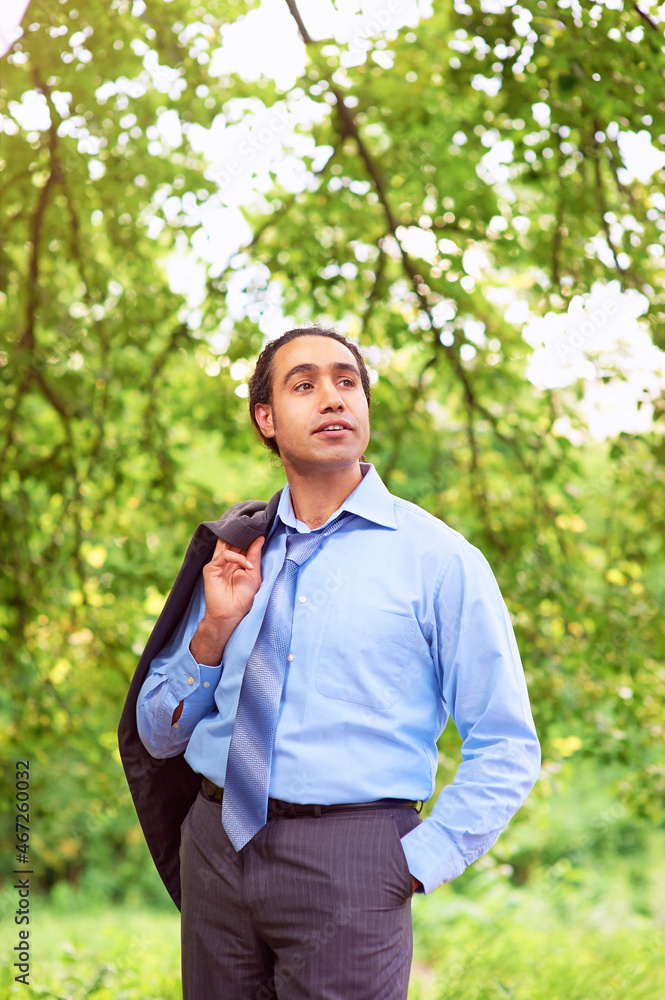 Happy relieved businessman stands in park with his jacket over his shoulder. Happy relieved businessman stands in park with his jacket over his shoulder.