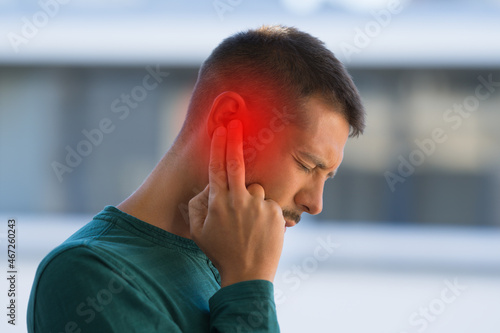 Man suffering because of strong earache or ear pain. Otitis photo