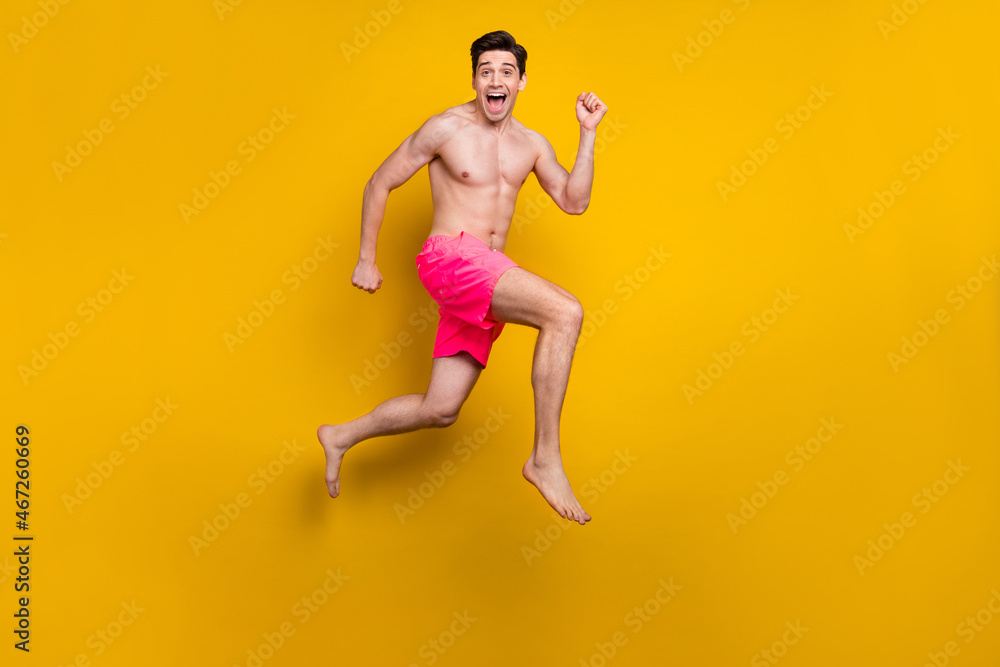 Full size profile photo of nice young guy jump wear pink shorts isolated on yellow background