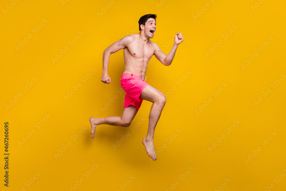 Full length body size view of attractive cheerful motivated guy jumping running isolated over shine yellow color background Full length body size view of attractive cheerful motivated guy jumping running isolated over shine yellow color background