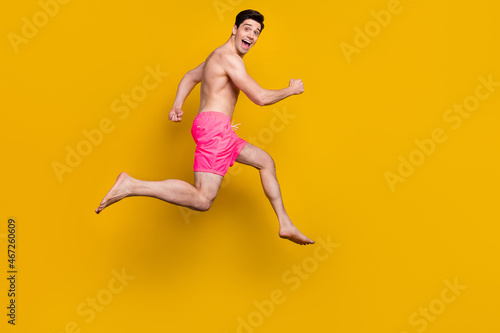 Full length profile side photo of young man happy positive smile go walk run jumper isolated over yellow color background