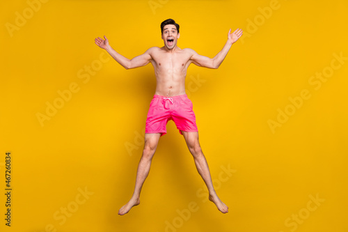 Full length photo of cool millennial guy jump wear pink shorts isolated on yellow background