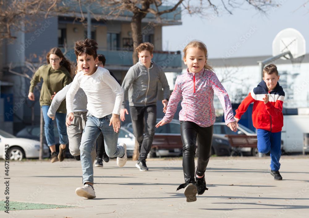 Large group of playful children running together at urban landscape