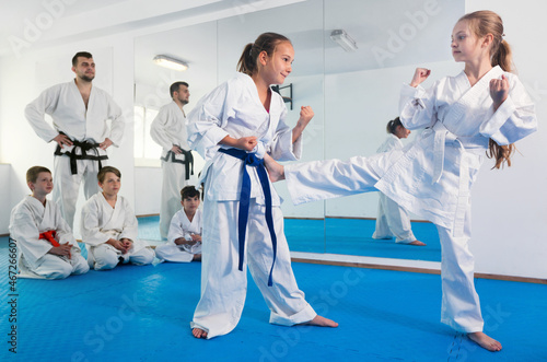 Happy pair of little girls practicing new karate moves during class