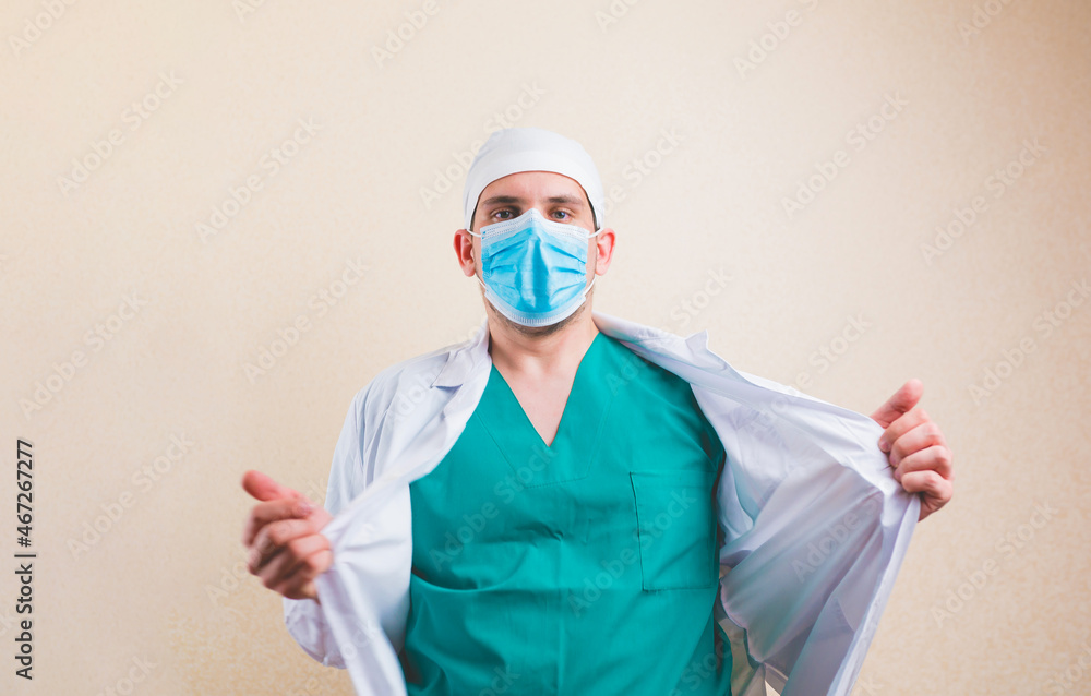 Doctor in protective medical mask and green suit opens his white coat isolated Doctor in protective medical mask and green suit opens his white coat isolated