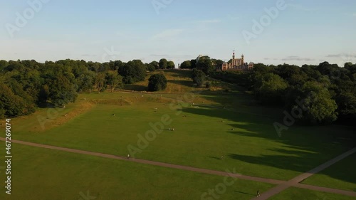 people enjoying day relaxing on green meadow in park. Greenwich Observatory up on hill. London, UK photo