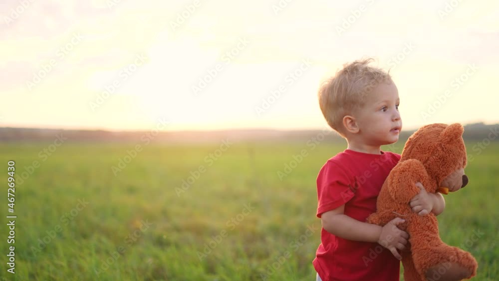 portrait of a baby boy with a toy teddy bear in his hands on nature in ...