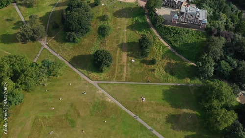 people sitting on lawn and relaxing near Greenwich Observatory. Tilt up reveal on landscape. London, UK photo