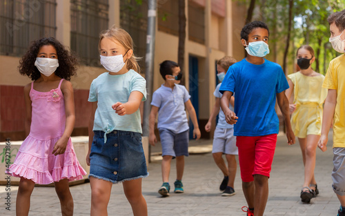 Group of positive children in masks walking together on the street