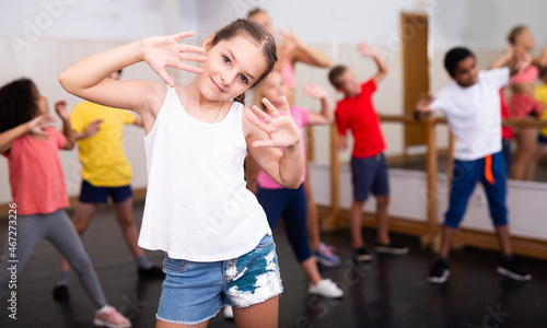 Portrait of little girl doing exercises during group class in dance center