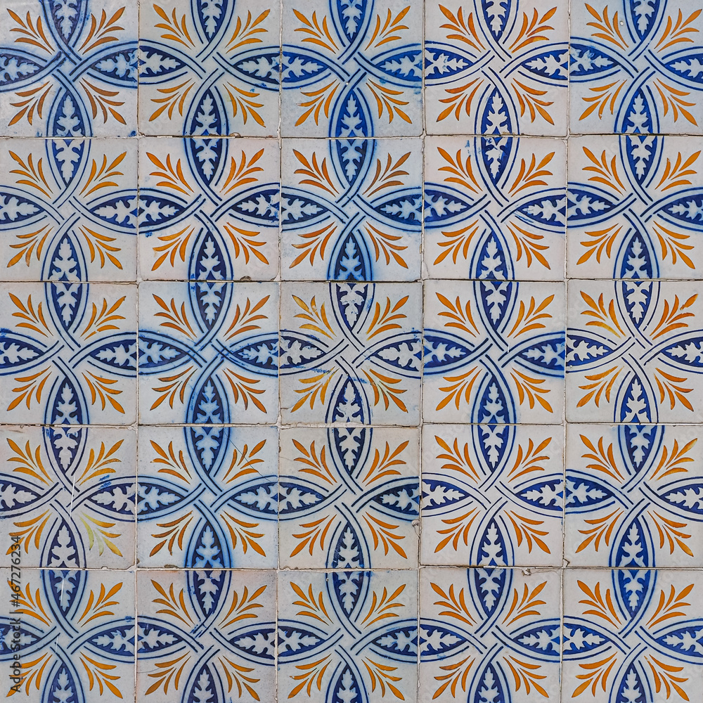 Abstract ornamental background. Fragment of old building wall, with ornate glazed tiles. White tiles with blue orange painted decorations. Azulejos, traditional Portuguese art, for architecture design
