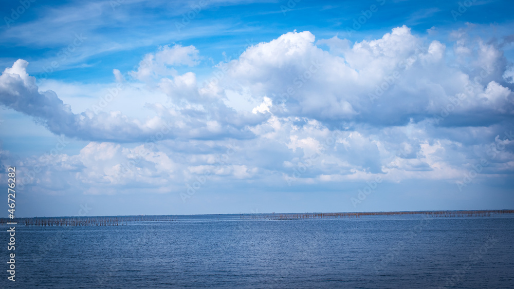 The vast sea with white clouds in the blue sky, beautiful nature.