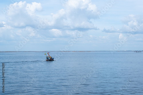Small fishing boats floating in the sea, blue sky with white clouds, beautiful nature.
