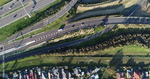 Smooth tracking aerial perspective shot from top down of vehicles entering the main carriage way of major highway interchange below. photo