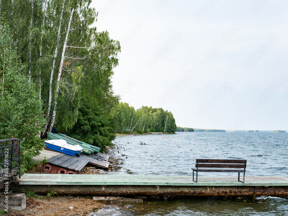 Fototapeta premium boats stand on the sandy shore. around trees, water, a pier. the beginning of summer. the swimming season is open. recreation centers are waiting for people, visitors, vacationers