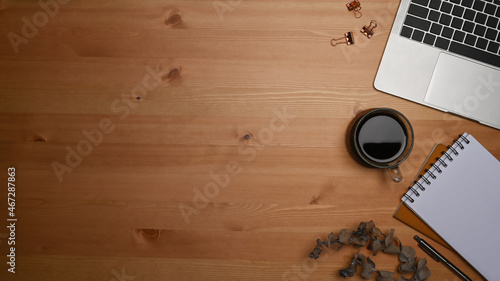 Computer laptop, notepad and coffee cup on wooden background.