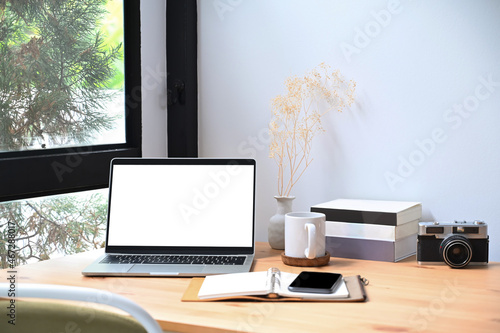 Stylish workplace with laptop computer, books and camera on wooden table. © Prathankarnpap