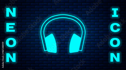 Glowing neon Noise canceling headphones icon isolated on brick wall background. Headphones for ear protection from noise. Vector