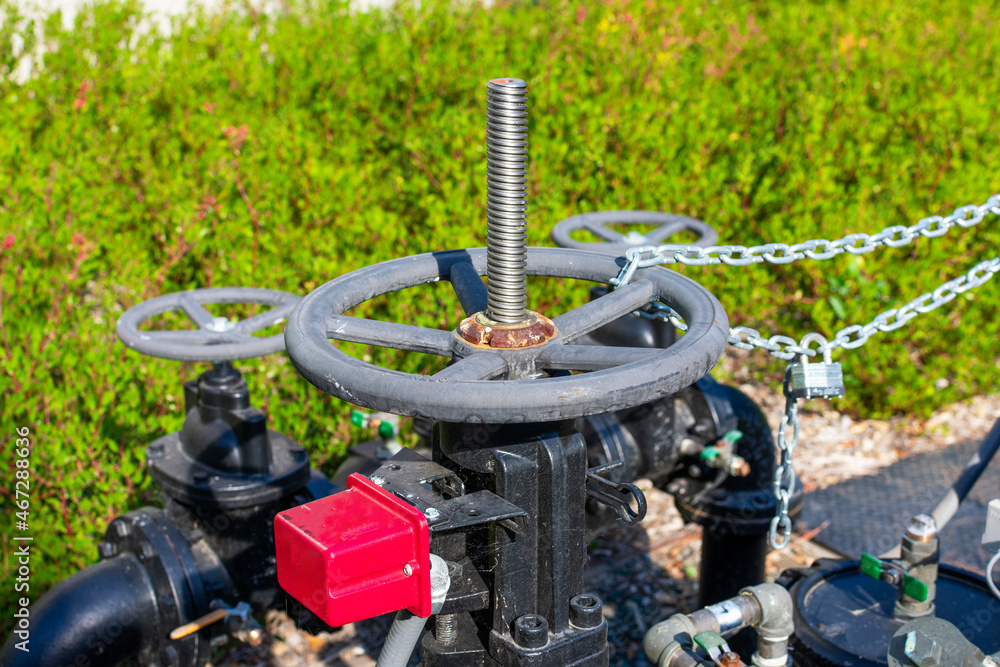 Manual hand wheel on valve controlling the main water supply system. Blurred green landscape background. Manual hand wheel on valve controlling the main water supply system. Blurred green landscape background.
