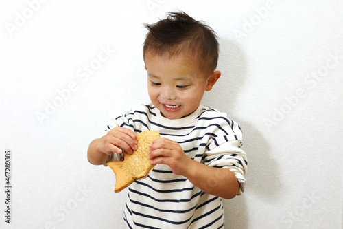 日本のスイーツ、鯛焼きを美味しく食べている男の子。