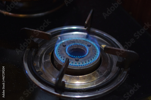 Gas stove burner top view. Propane and butane gas burning in blue flames in the dark.