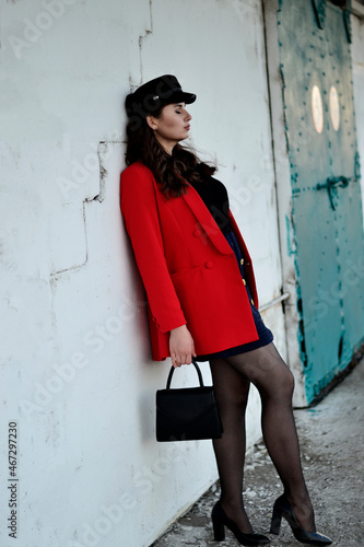 A young long-haired brown-haired woman in a black beret and a red coat on the station platform