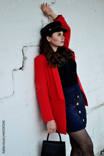 A young long-haired brown-haired woman in a black beret and a red coat on the station platform