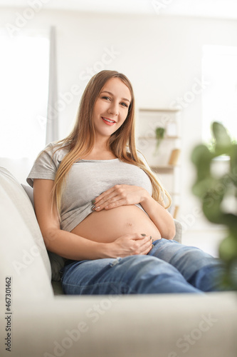 Young pregnant woman sitting on grey sofa at home Free Download Young pregnant woman sitting on grey sofa at home - GFXLoad