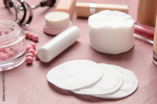Cotton pads and decorative cosmetics on color table, closeup