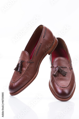 Footwear Ideas. Pair of Traditional Formal Stylish Brown Pebble Grain Tassel Loafer Shoes Together In Line Against White Surface.