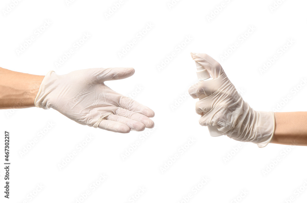 Woman in medical glove spraying antiseptic onto man's hand on white background Woman in medical glove spraying antiseptic onto man's hand on white background