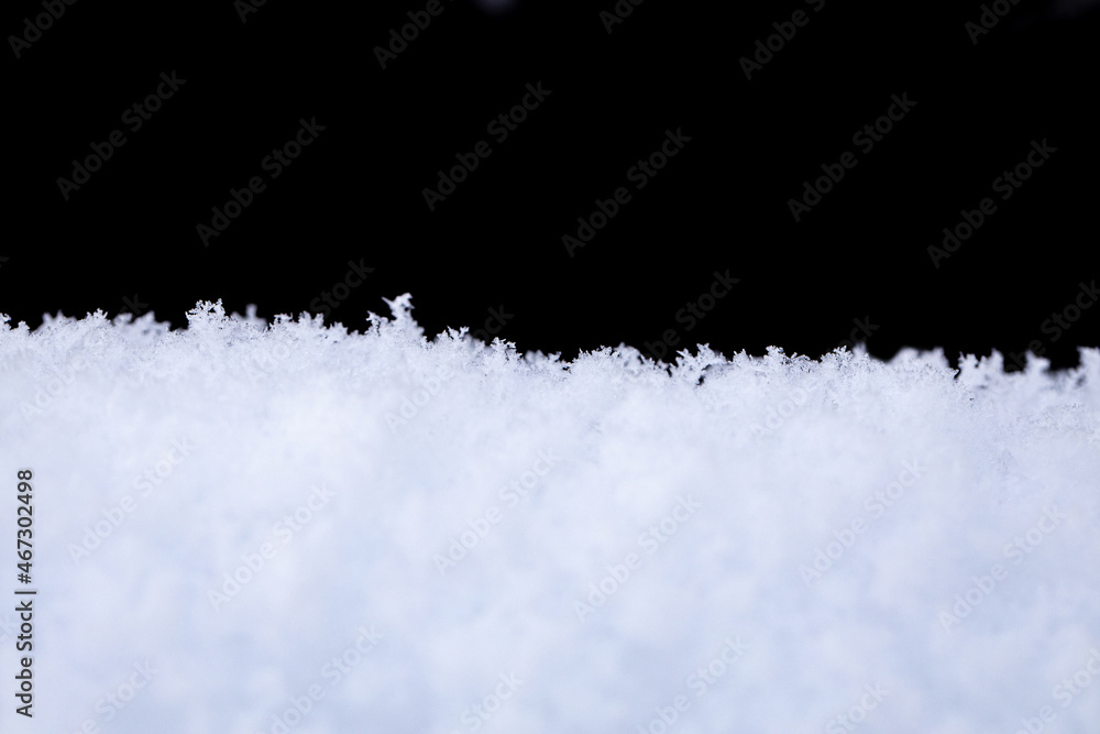 Snowdrift, in front of a black background. Fluffy snow edge on winter sunny day on black background.