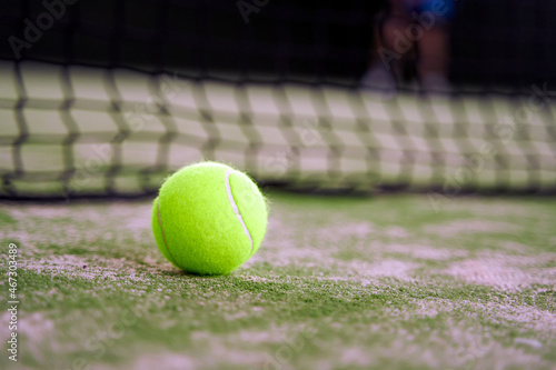 Tennis Ball on the Court Close up with Net in the Background © JoseIMartin