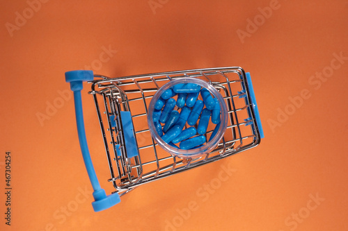 Wallpaper Mural Blue capsules in a small supermarket trolley on an orange background. Delivery of pills from pharmacies.  Torontodigital.ca
