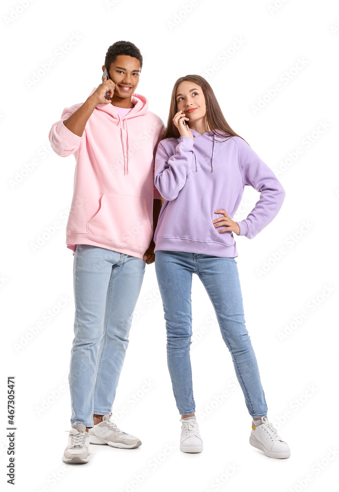Stylish young couple in hoodies talking by mobile phones on white background Stylish young couple in hoodies talking by mobile phones on white background