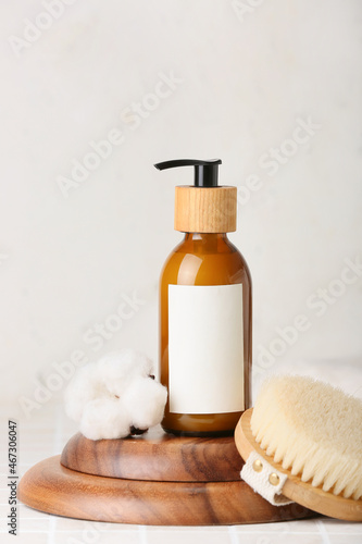 Composition with bottle of cosmetic product  massage brush and cotton flower on light background  closeup