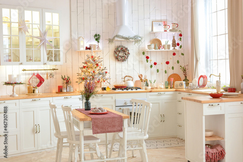 Interior of a light white сhristmas kitchen with red decor elements in the Scandinavian style. Christmas decorations. Breakfast