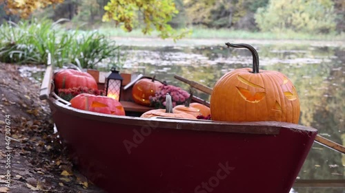 pumpkin carved with smoke in boat on pond in autumn, Halloween celebrating concept 