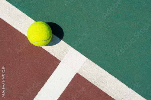 Yellow tennis ball lying on line of the red and green court. Flat lay view. Space for text © Dmytro_Mykhailov