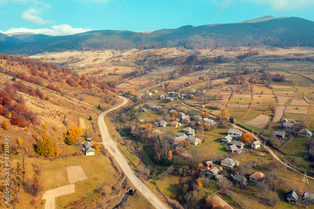 Aerial view of the countryside, country road, and village in the mountain valley. Mountain landscape in autumn