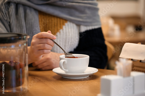 Young woman drinking tea at table in cafe, closeup