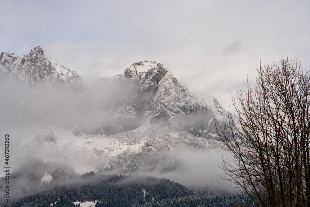 Obraz premium Wilder Kaiser in Tirol Österreich mit ersten Schnee im Jahr umhüllt von Wolken und Nebelschwaden.