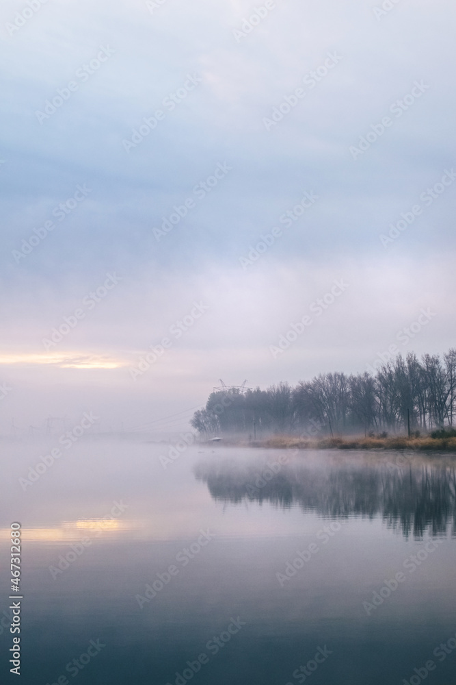 Background. Mountain lake in the fog. Magic morning. Fog spreads beautifully over the water surface. The trees are almost invisible. Clouds and sky are reflected from the surface