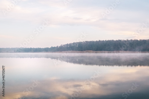 Fototapeta Naklejka Na Ścianę i Meble -  Background. Mountain lake in the fog. Magic morning. Fog spreads beautifully over the water surface. The trees are almost invisible. Clouds and sky are reflected from the surface