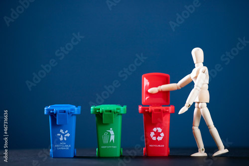 Fotografie Wooden man with set of bins for the selective collection of waste for recycling