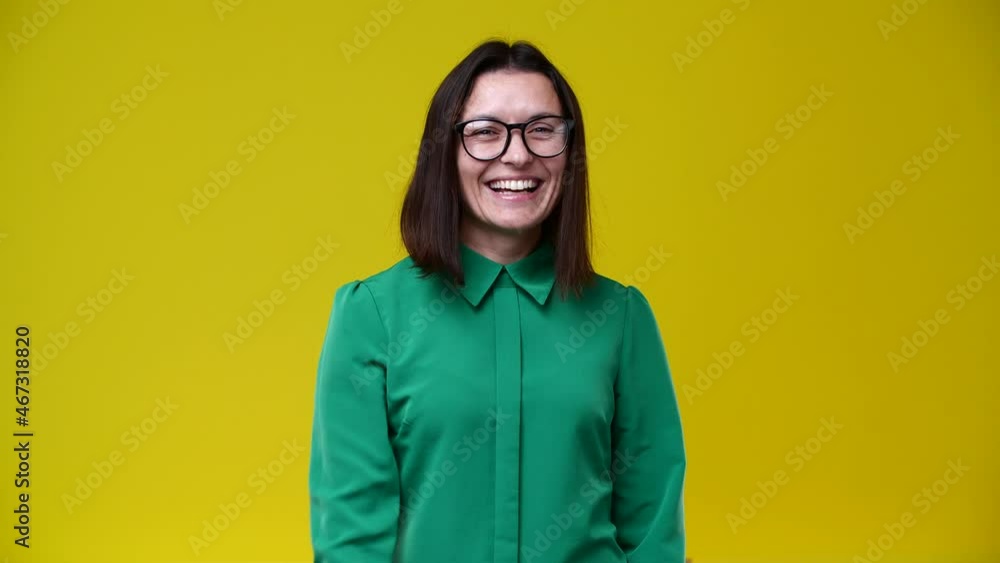 the girl looks at the camera and shows that you would call her, she is wearing glasses, dressed in a green shirt, short hair, brunette, the background is yellow the girl looks at the camera and shows that you would call her, she is wearing glasses, dressed in a green shirt, short hair, brunette, the background is yellow