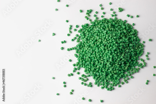 green granules of polypropylene or polyamide on a white background. Plastics and polymers industry. Copy space. Macro photo