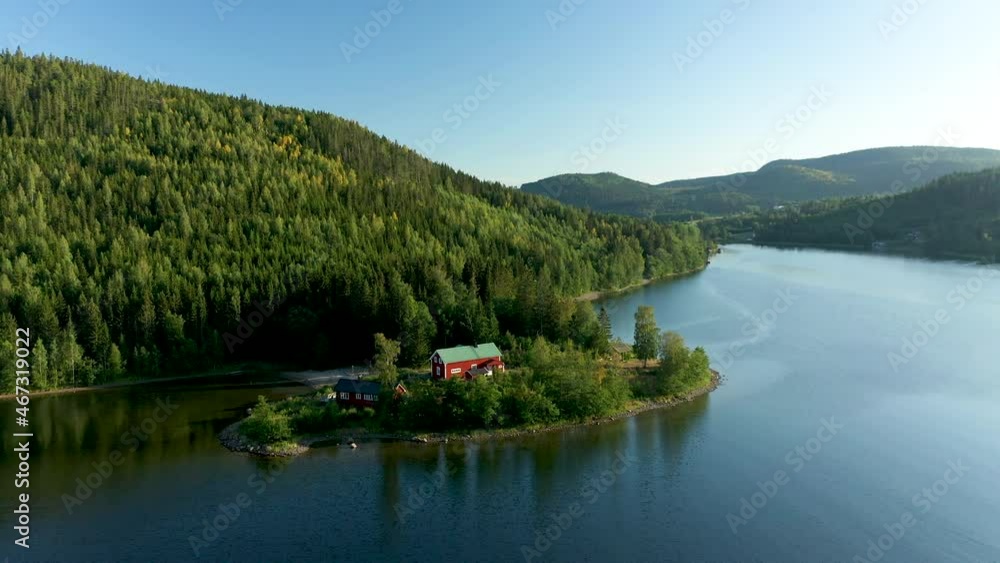 Red remote cabin at the foot of a mountain hills side in beautiful coastal fjord landscape Red remote cabin at the foot of a mountain hills side in beautiful coastal fjord landscape